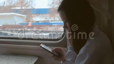 疲惫的年轻女子在火车上用手机看视频。